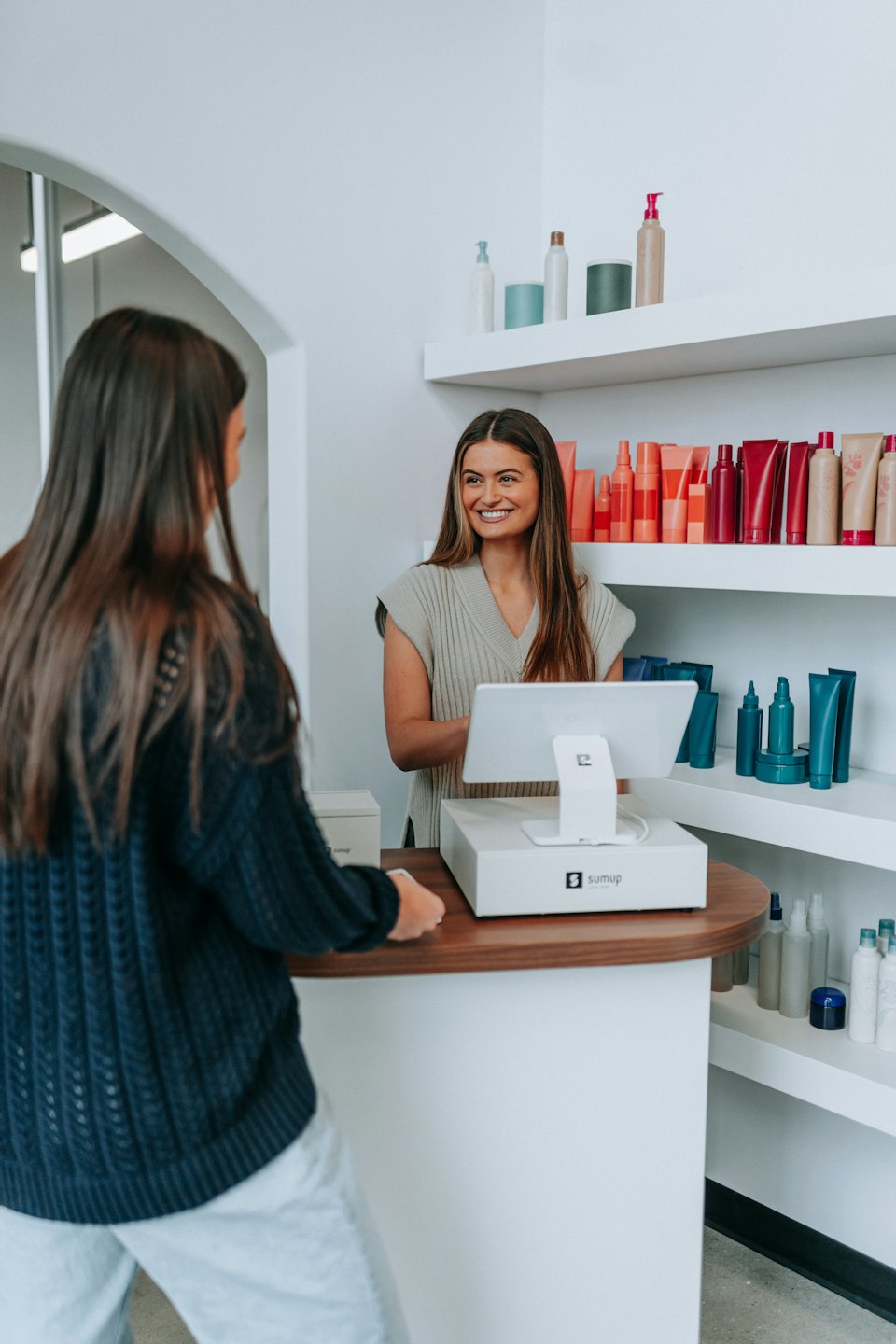 Employee smiles at customer at a beauty product checkout counter.
