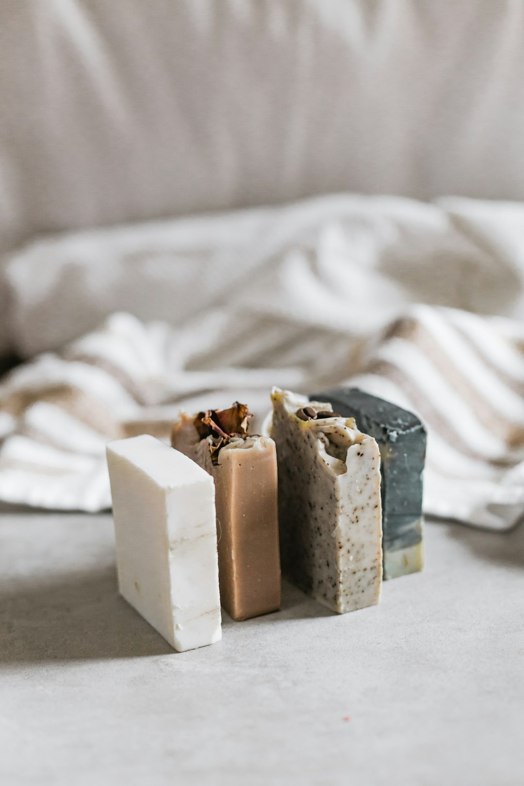 Four colorful bars of artisan soap on a gray surface.